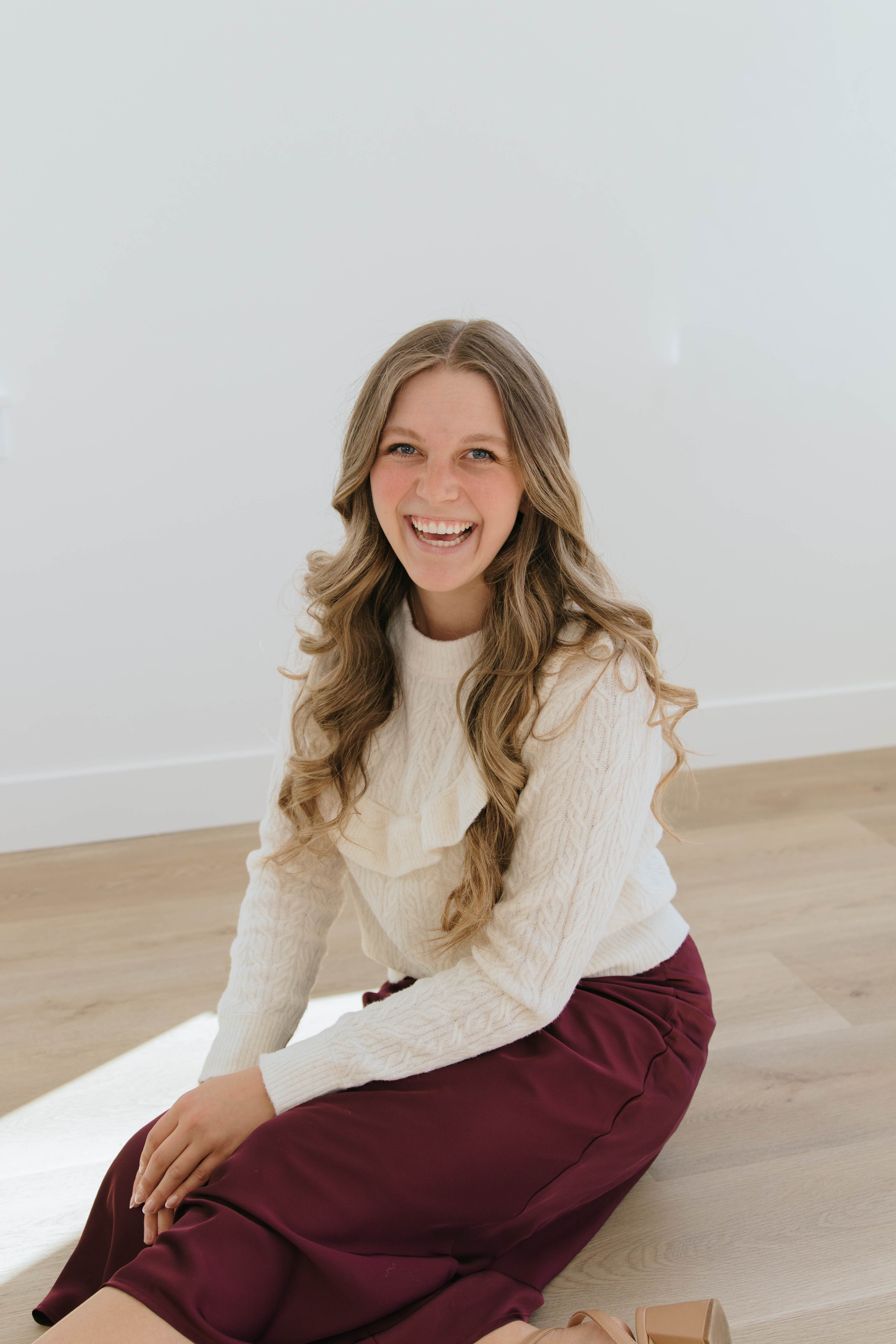 Founder smiling in a close-up portrait against a pale studio wall.